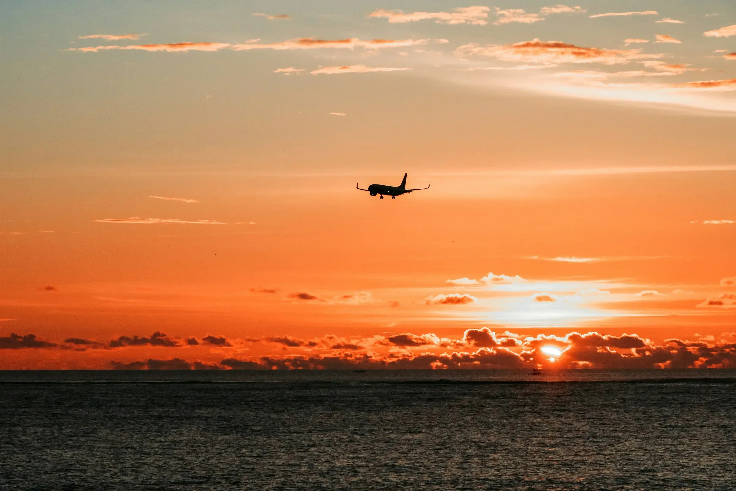 A jet silhouetted against an orange sunset over water