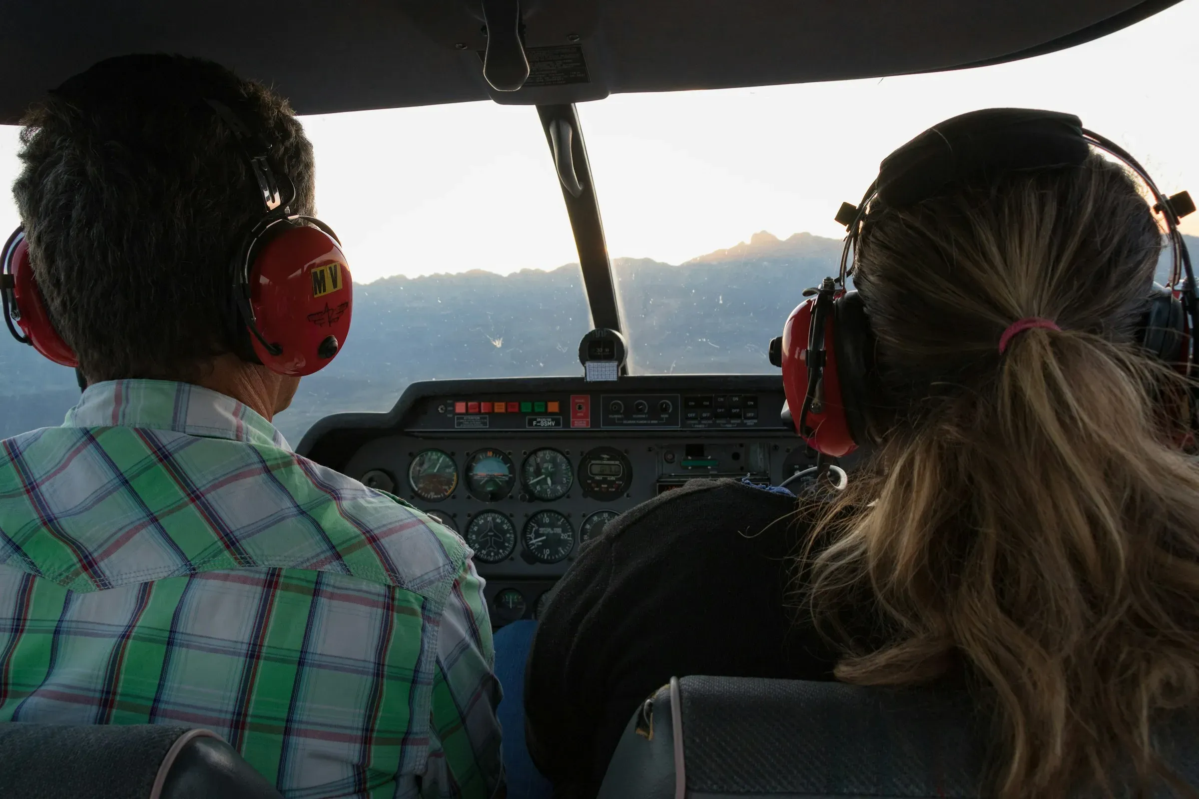 A pilot and passenger wearing headsets in the cockpit of a small plane
