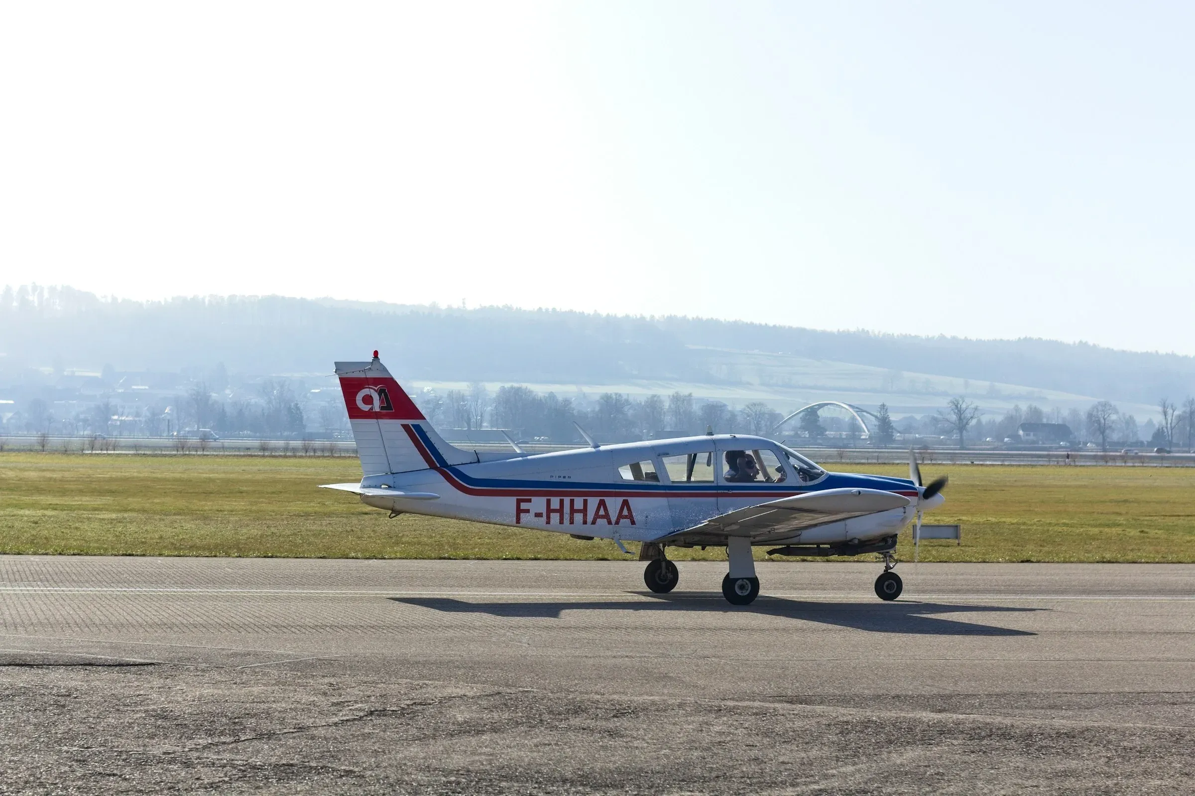 A red and white single-engine Piper taxiing on a runway
