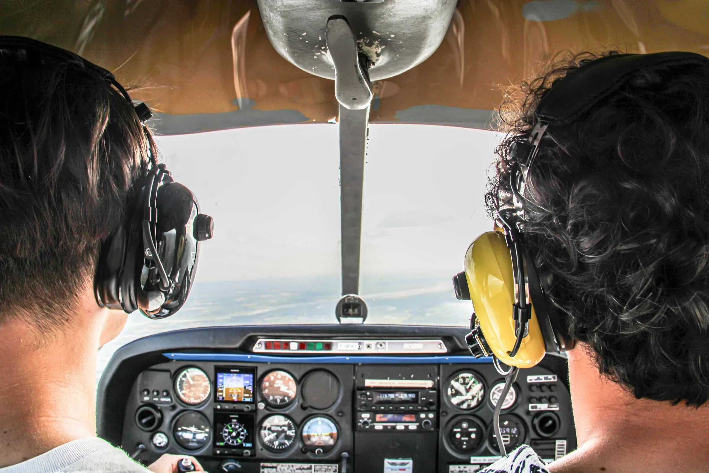 Two pilots side by side in a cockpit above the clouds