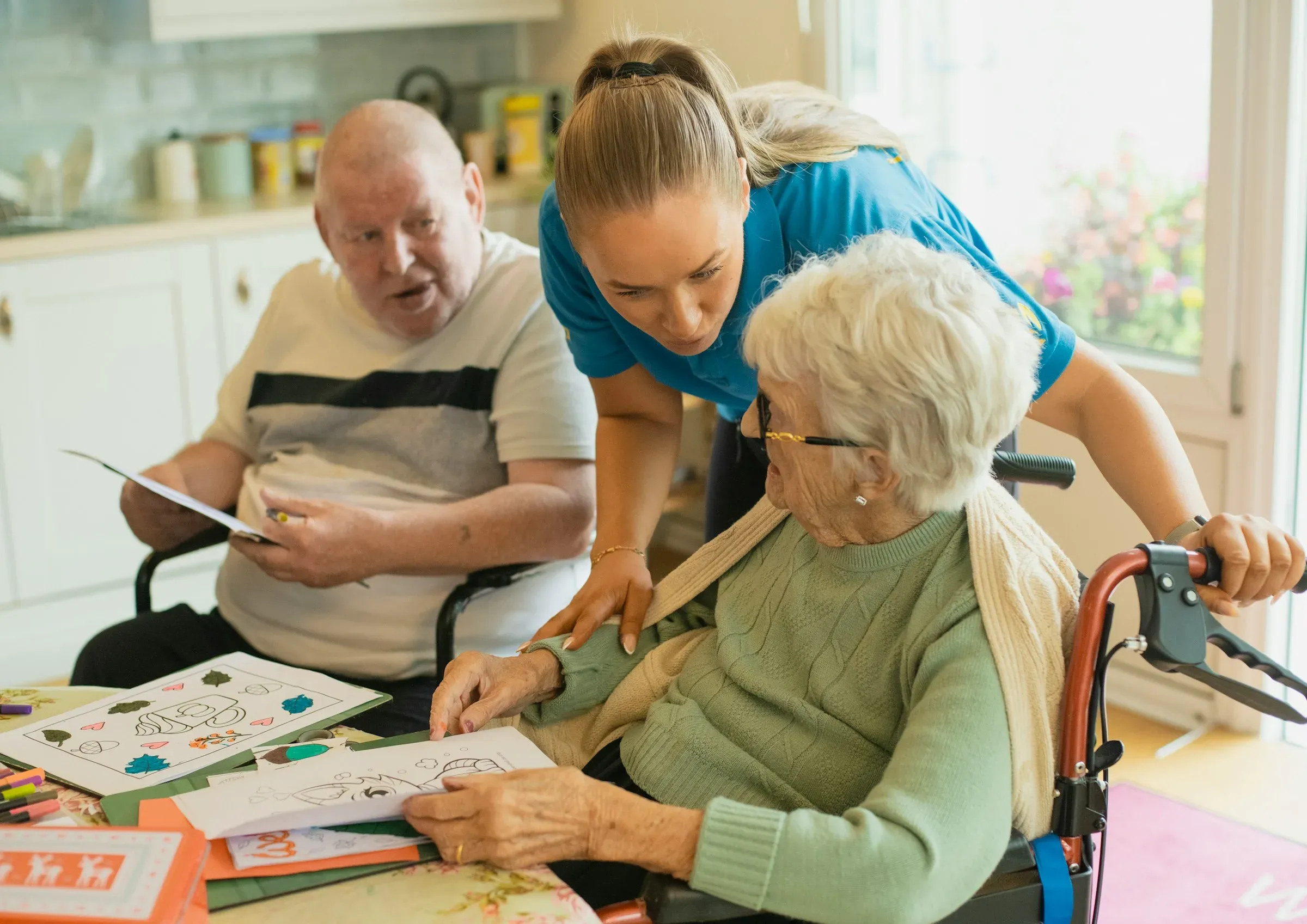 A volunteer helping an elderly couple with an activity at a table